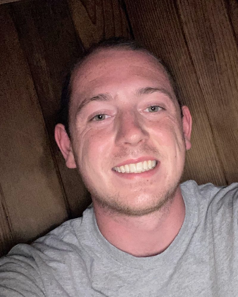 Alexander Koontz, entrepreneur and life consultant, smiling in a gray T-shirt